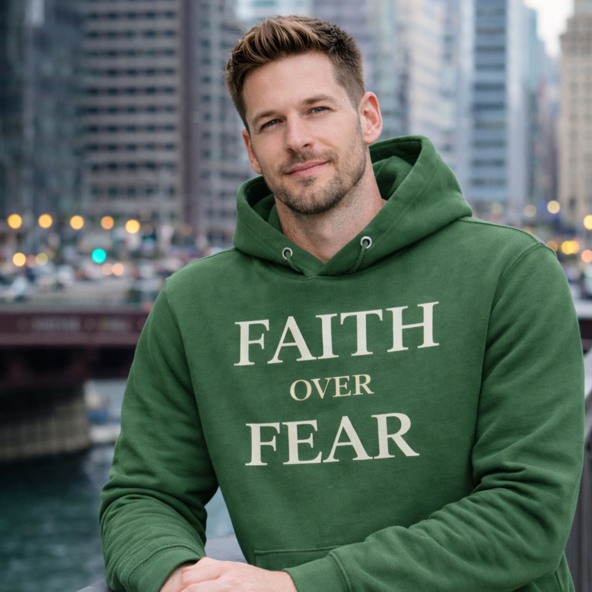 Man wearing a green hoodie with 'Faith Over Fear' text in an urban setting