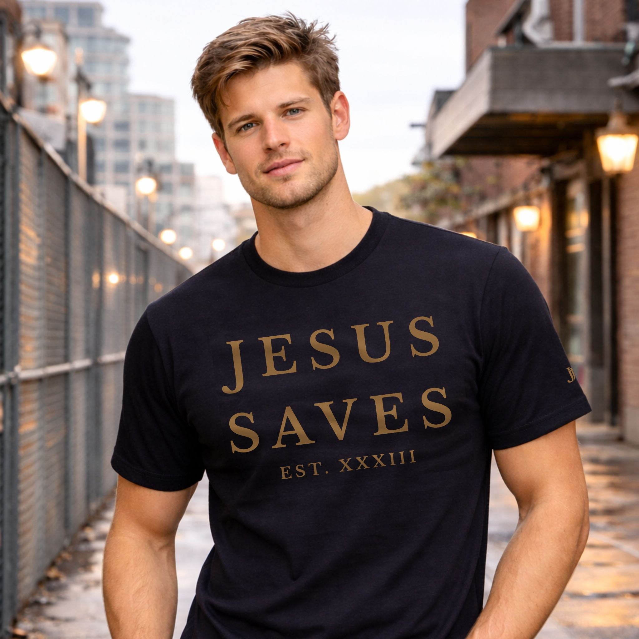Man wearing a black t-shirt with 'JESUS SAVES' text in gold, standing on a city street.