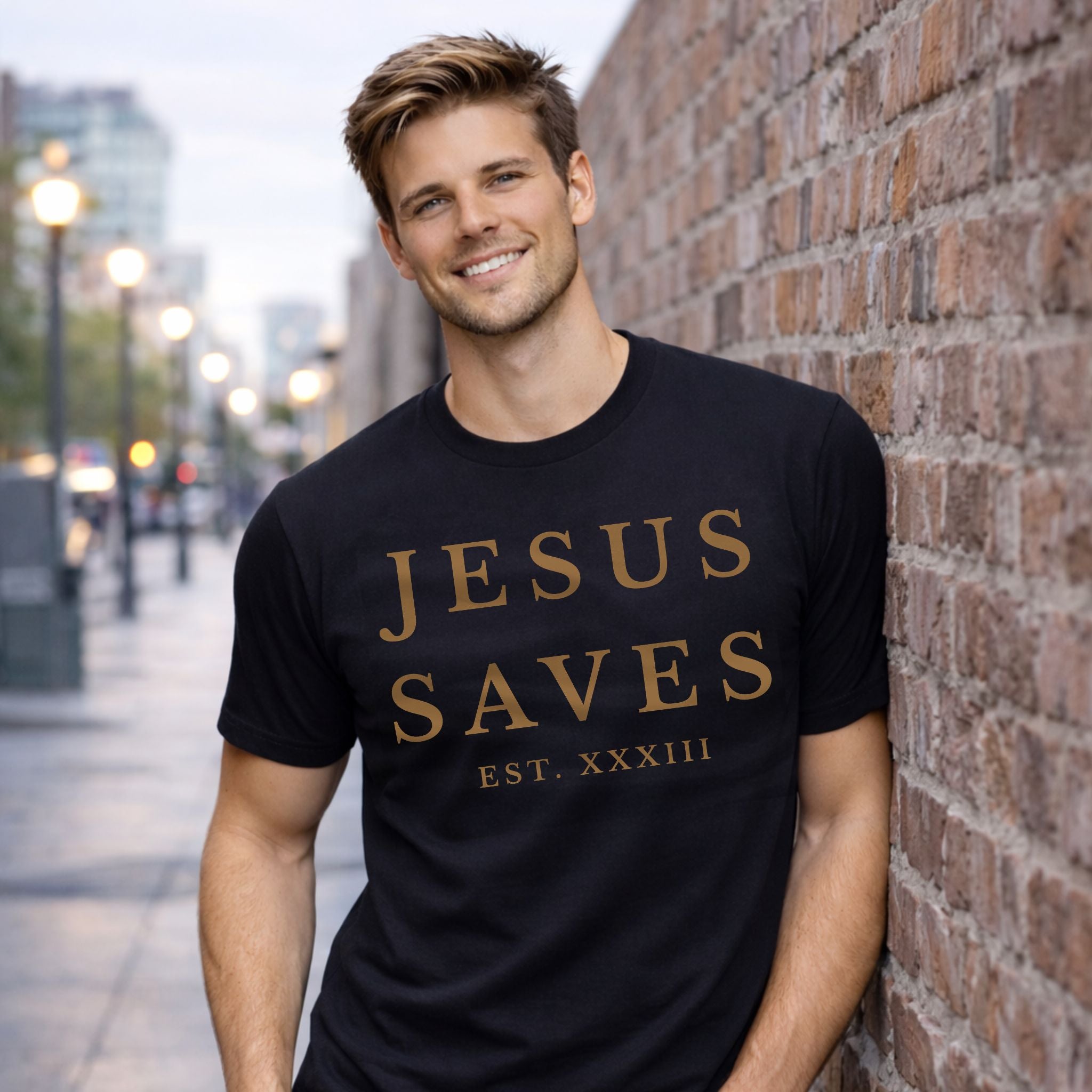 Man wearing a black t-shirt with 'Jesus Saves' text, standing against a brick wall.