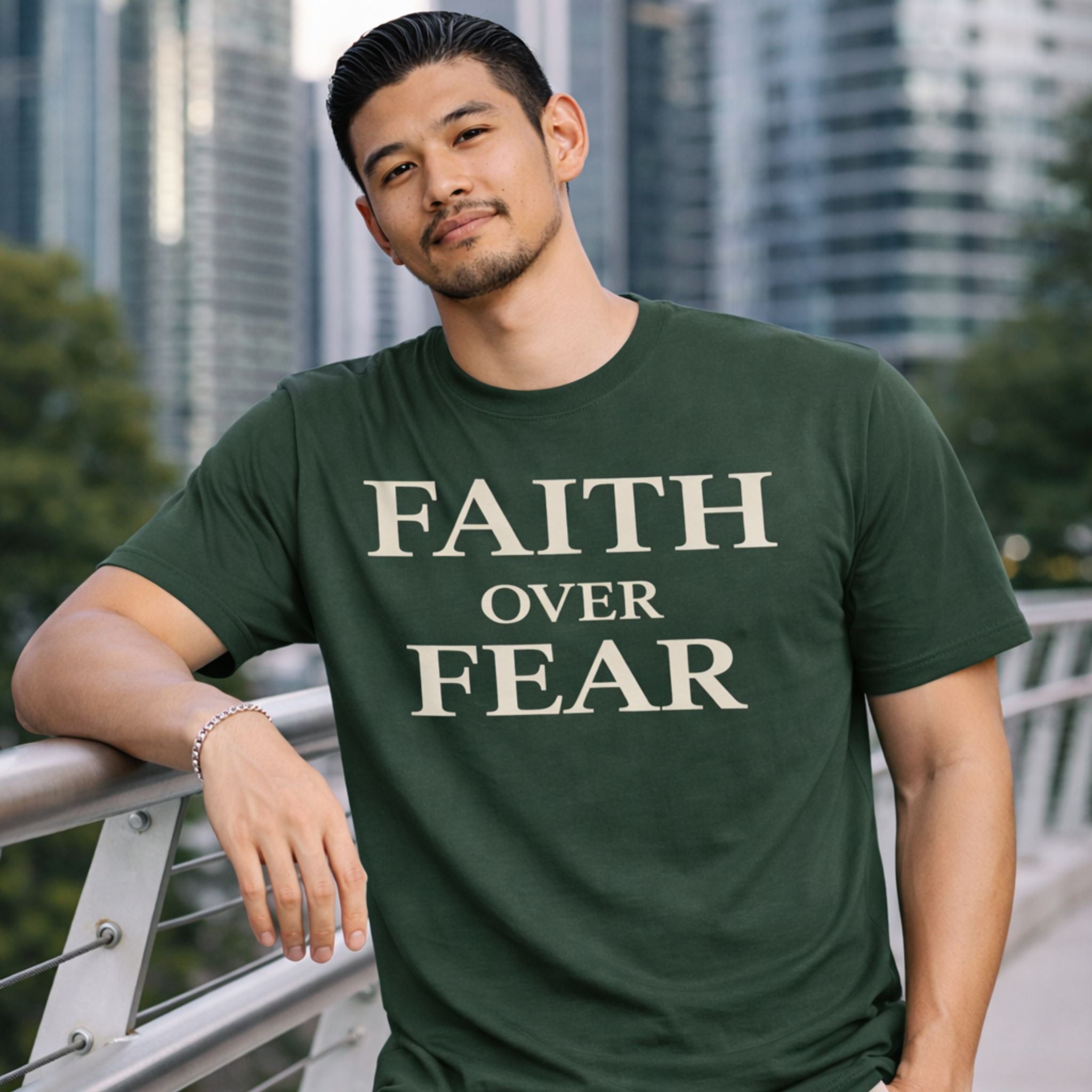 Man wearing a green t-shirt with 'Faith Over Fear' text, standing outdoors with a cityscape background.