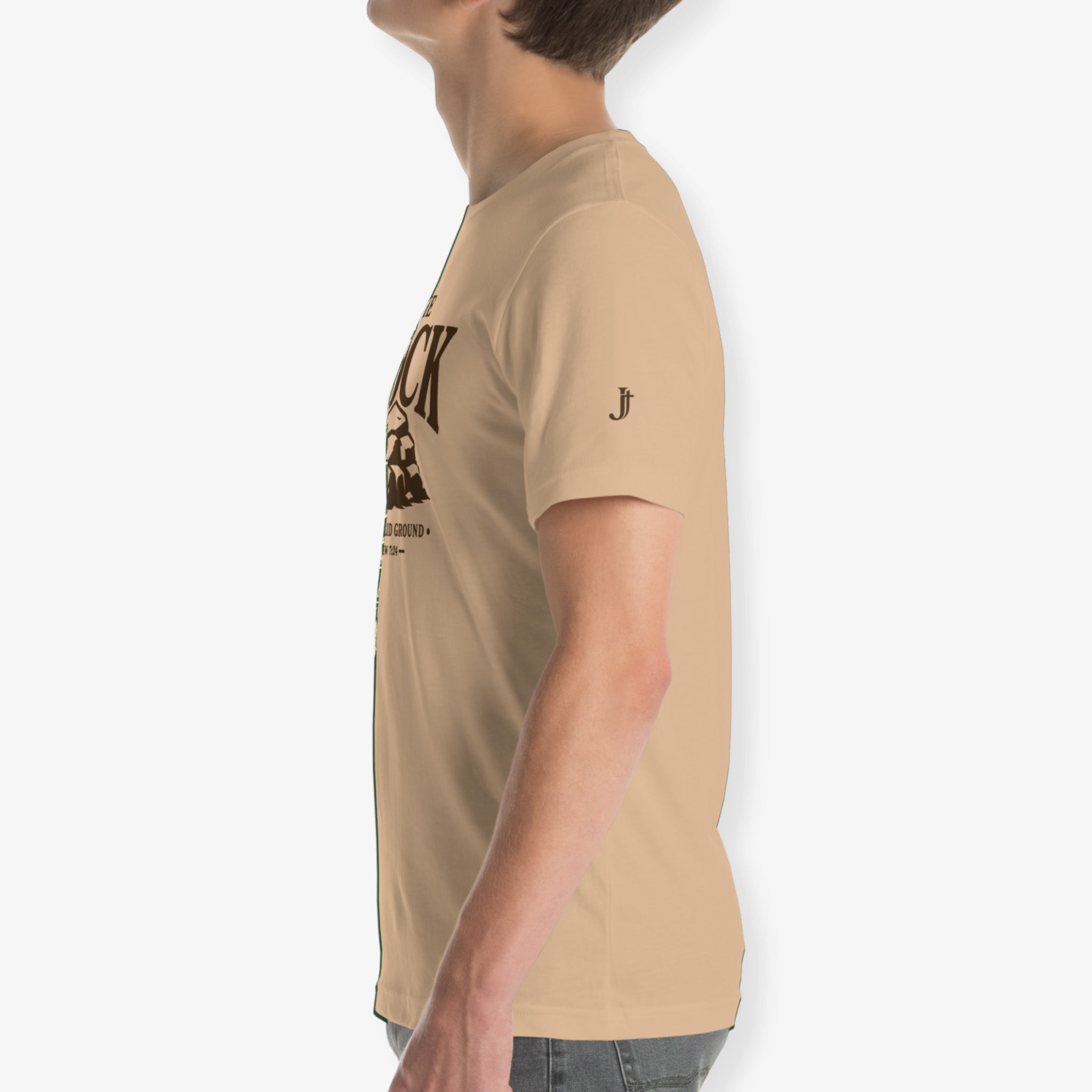 A side-profile view of a man wearing a beige crew-neck t-shirt with a dark brown graphic print on the front and a small logo on the left sleeve, set against a plain light gray background.