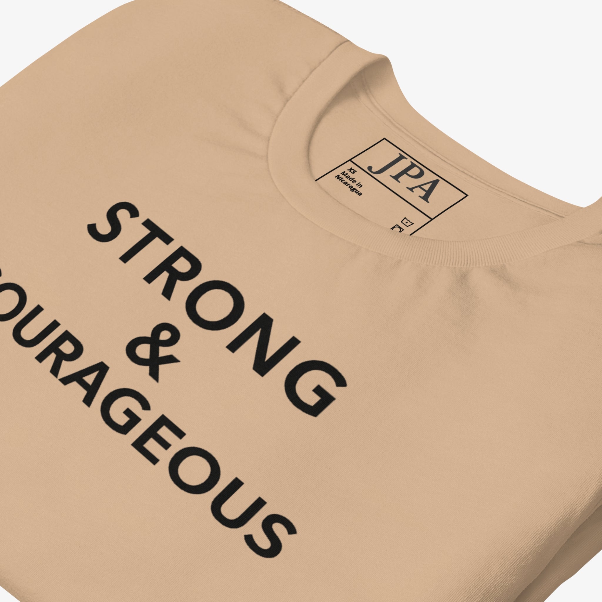 Beige t-shirt with 'STRONG & COURAGEOUS' text and JPA logo on a light gray background