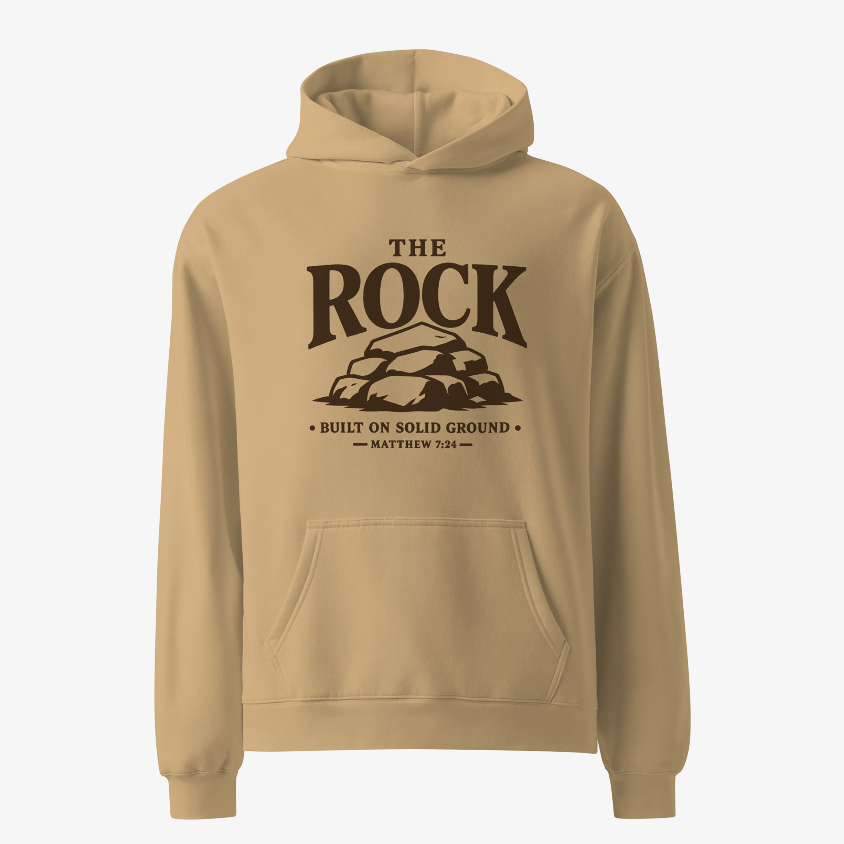 A tan pullover hoodie with a dark brown graphic on the chest reading 'THE ROCK BUILT ON SOLID GROUND MATTHEW 7:24' above a rock illustration, shown on a light gray background.