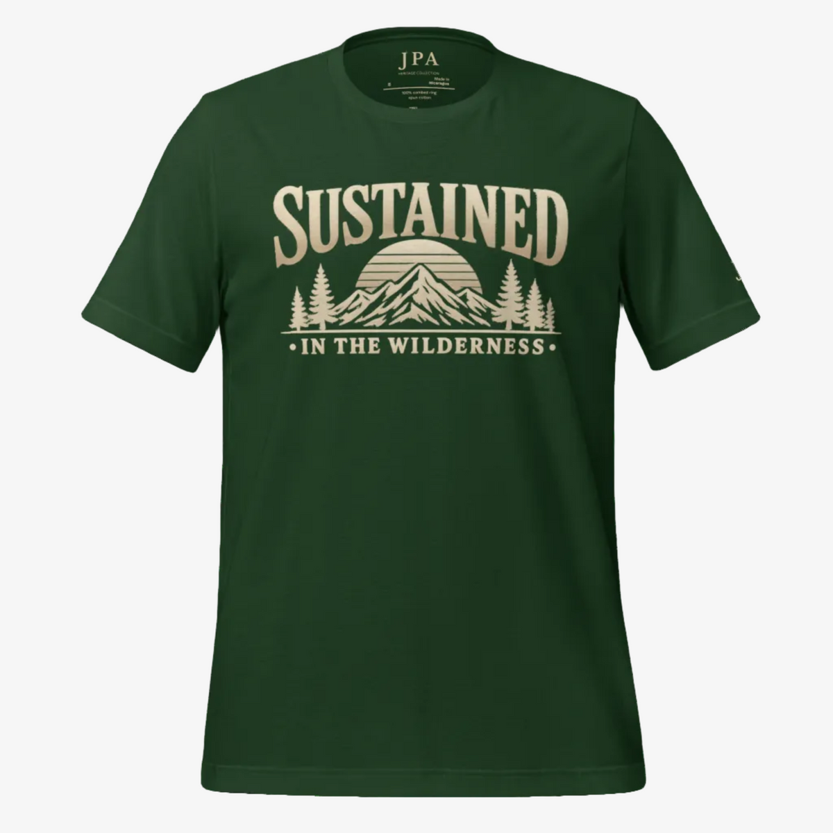 A dark green short-sleeve t-shirt with a beige graphic print on the front that reads 'SUSTAINED IN THE WILDERNESS' above a mountain and pine tree illustration. The brand 'JPA' is visible inside the collar.