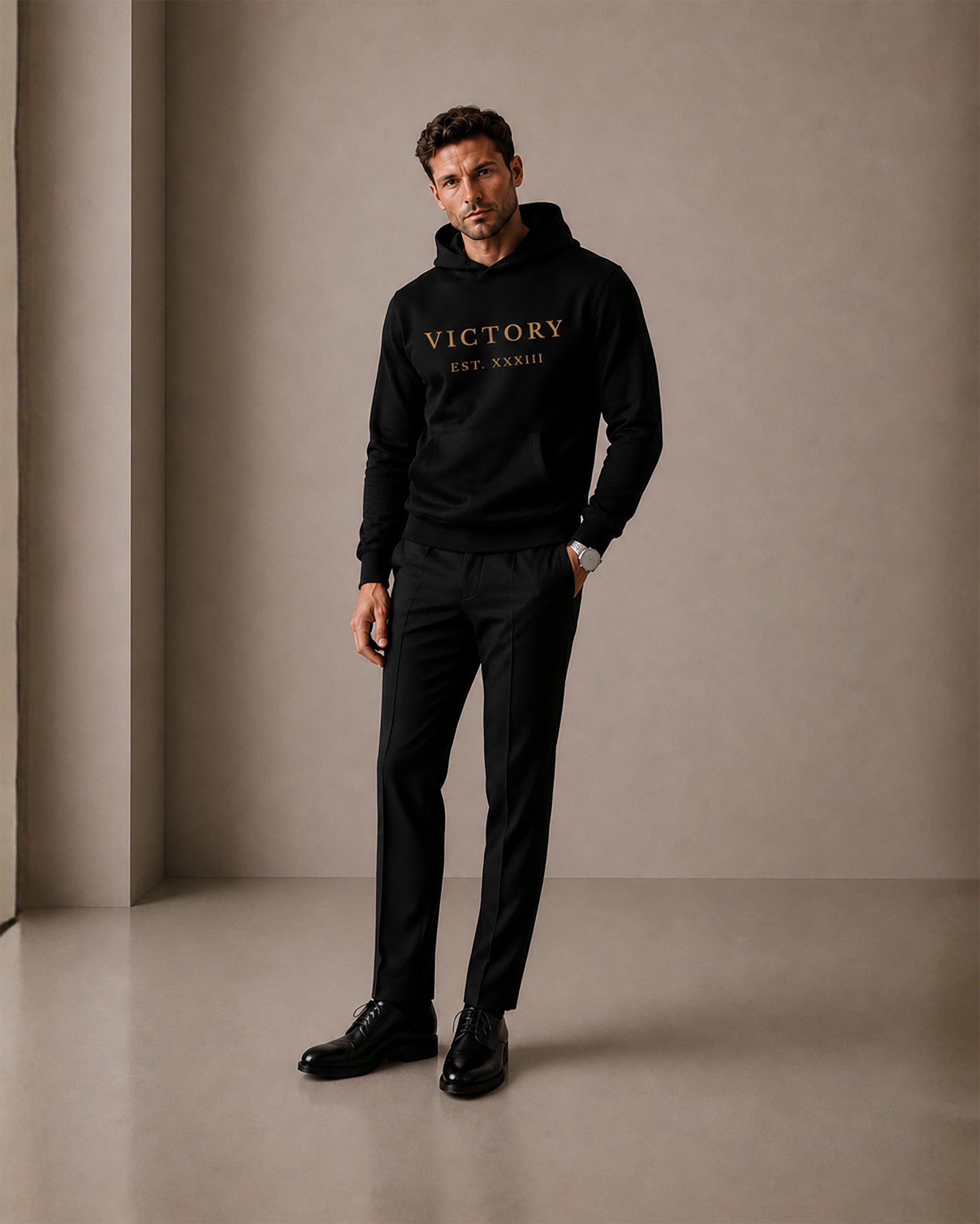 Man wearing a black hoodie with 'VICTORY' text, standing against a plain background