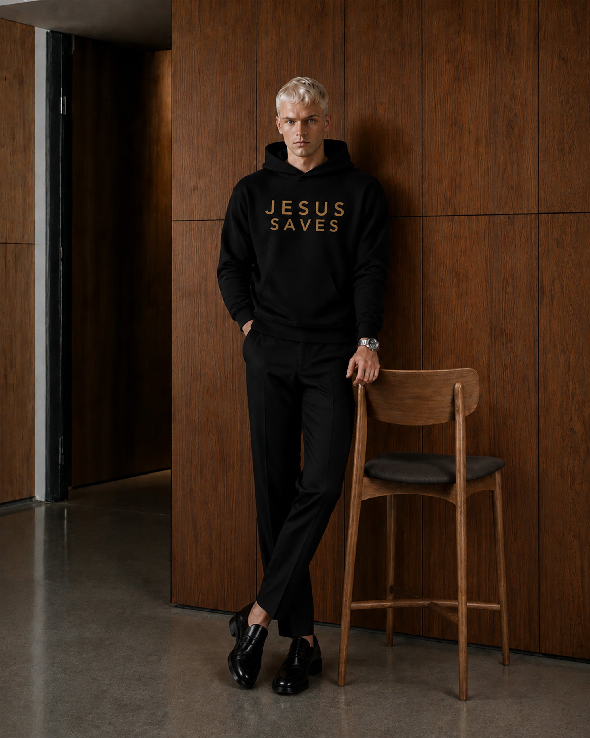 Person wearing a black hoodie with 'JESUS SAVES' text in a modern interior setting.