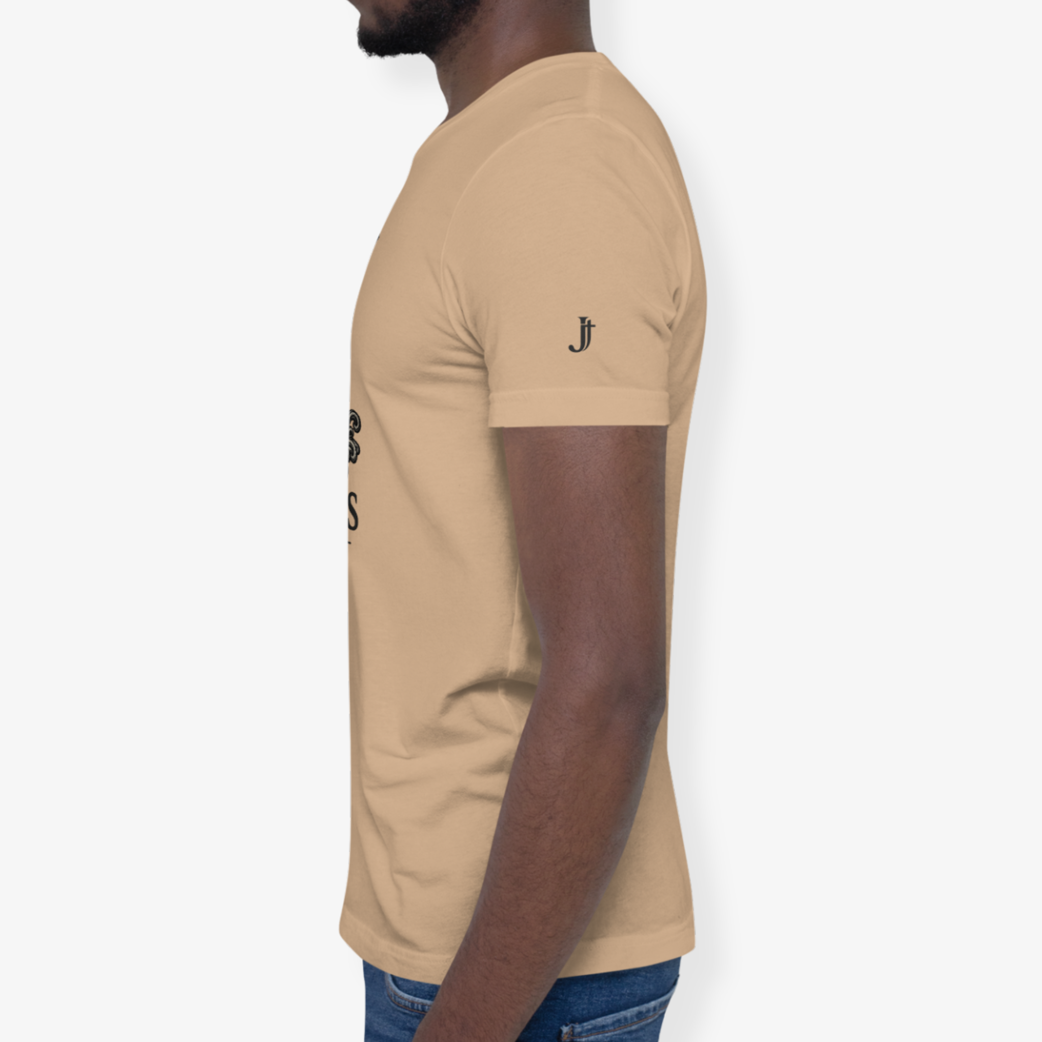 A man shown from the side wearing a beige crew-neck t-shirt with a small black graphic on the sleeve and partial black text on the chest, paired with blue jeans against a light gray background.