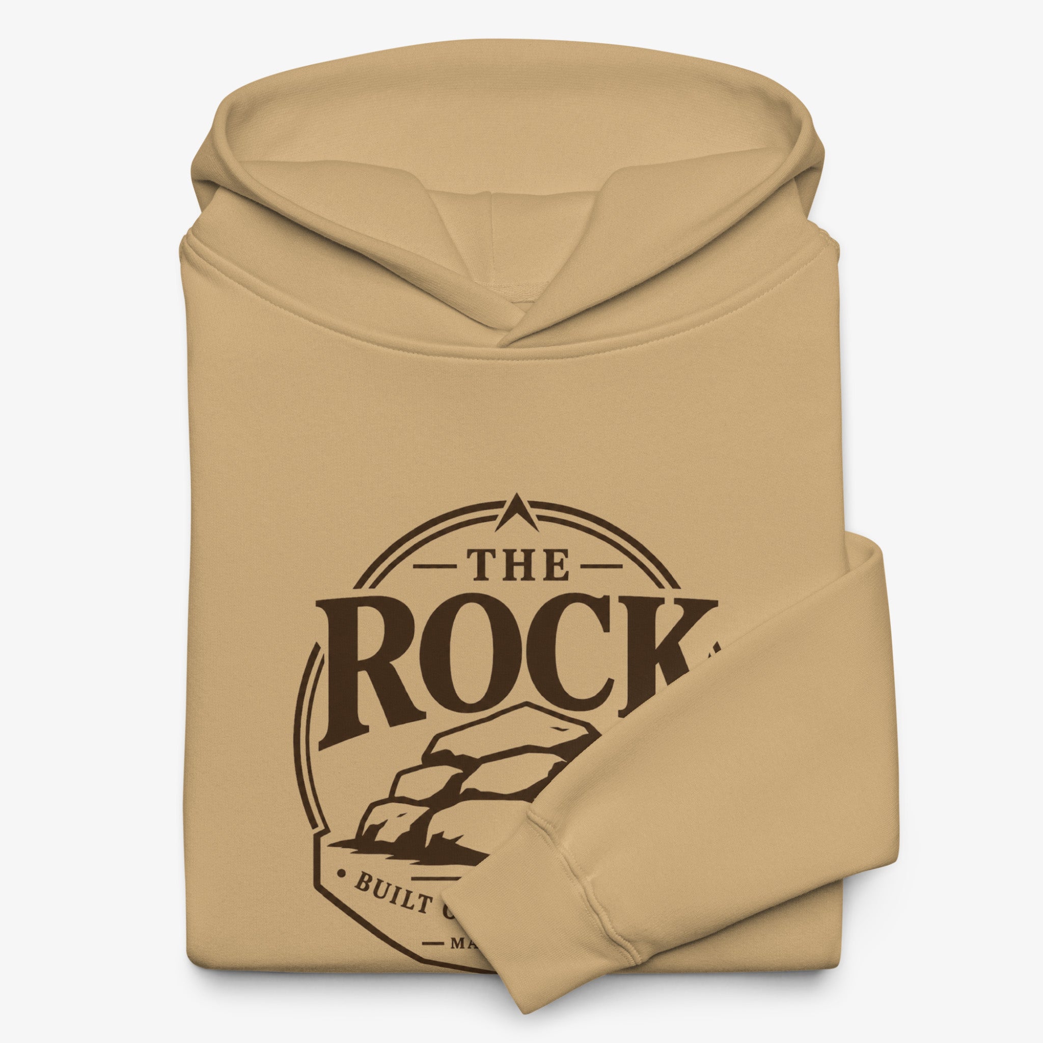 A folded tan hoodie with a dark brown graphic print on the front that reads 'THE ROCK BUILT.